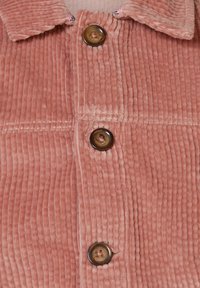 Rosa Cordhemd mit Kragen, versehen mit vertikalen Rippungen, vier großen braunen Knöpfen und kontrastierenden Nähdetails.