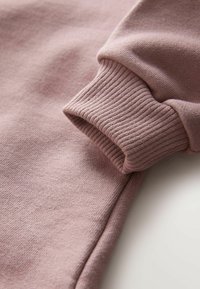 Lilla puuvillane sweatshirt varrukas, millel on soonikkoostriga tekstuur ja peened õmblused. Kanga näib olevat pehme ja elastne.
