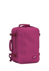 Borsa da cabina fucsia realizzata in tessuto resistente, con chiusura a zip, maniglia laterale e spallacci regolabili per una maggiore sicurezza.