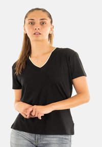 T-shirt nero a V con design aderente e maniche corte, dotato di un colletto chiaro a contrasto e una texture morbida e liscia.