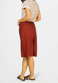 Shorts couleur rouille avec une coupe décontractée, taille élastique et poches latérales, associés à un haut à manches courtes à motif.