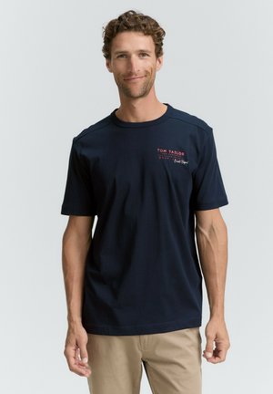 Marineblaue Kurzarm-T-Shirt aus Baumwolle mit Rundhalsausschnitt und rotem gesticktem Logo auf der Brust. Bietet eine lässige Passform und eine glatte Textur.