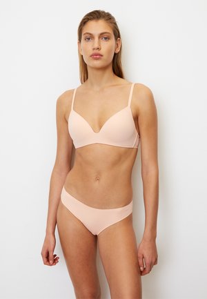 Set di lingerie rosa chiaro composto da un reggiseno modellato e liscio con spalline sottili e un perizoma a vita bassa abbinato. Design minimalista, texture senza cuciture.