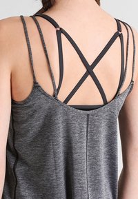Szary sportowy top na ramiączkach z tyłem typu racerback i skrzyżowanymi paskami, wykonany z lekkiego, teksturowanego materiału.