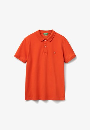 Polo de manga corta naranja brillante con dos botones, pequeño logotipo blanco y rojo en el lado izquierdo del pecho, y una etiqueta de la marca verde dentro del cuello.