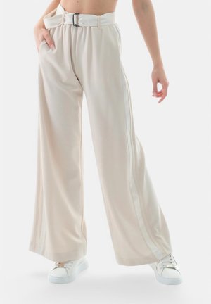 Pantaloni beige a gamba larga con frontale plissettato, una cintura con fibbia metallica, strisce laterali e tasche. Realizzati in un tessuto liscio e leggero.
