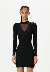 Vestito nero a costine con maniche lunghe, con un neckline a V in rete e accenti scintillanti sulle spalle. Vestibilità slim, texture morbida.