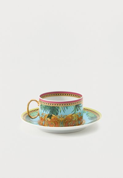 Ensemble tasse en porcelaine et soucoupe avec anse en or, décoré de feuilles de palmier bleu et vert, ainsi que de motifs ornés orange et or sur fond blanc.