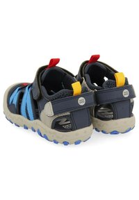 Zapatos de agua azul y marino con correas ajustables, parte trasera texturizada y suelas de goma con acentos azules. Diseñados para comodidad y agarre.