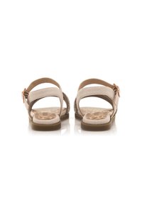 Sandali in suede beige con due cinturini regolabili, suola piatta e una fibbia decorativa. Presentano una soletta con motivo per una maggiore aderenza.