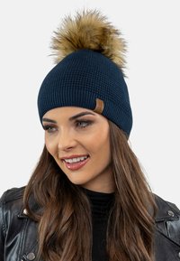 Căciulă tricotată bleumarin cu un finisaj texturat, cu un pom-pom mare din blană sintetică; prezentând un mic patch din piele cu logo.
