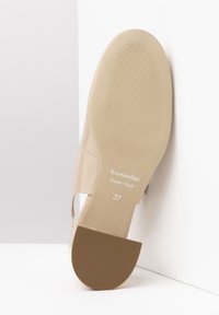 Suela de zapato de charol beige con agarre de goma texturizada. Presenta un tacón resistente y una marca en relieve. Talla marcada como 37.
