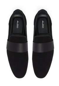 Paire de mocassins noirs sans lacets avec une large bride en cuir sur le dessus et "ALDO" imprimé sur les semelles intérieures, vue de dessus sur fond blanc.