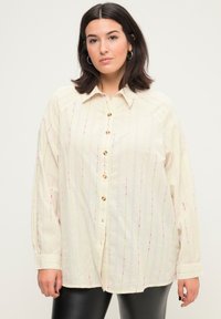 Camicia button-up beige chiaro con righe verticali multicolori, maniche lunghe e vestibilità comoda. Realizzata in un tessuto testurizzato.
