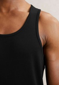 Czarny pr�ążkowany top na ramiączkach z okrągłym dekoltem, prezentujący teksturowany materiał i dopasowany krój, podkreślający widok ramion i górnej części ramion.