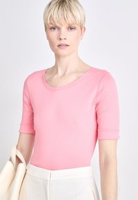 Roze top met korte mouwen en een ronde halslijn, met een aansluitende pasvorm, gemaakt van gladde stof, gecombineerd met een crèmekleurige rok.
