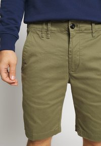 Olivegröna shorts i en texturerad bomullsmix, med bältesöglor, knappstängning fram och sidofickor.