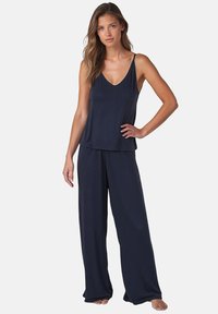 Marineblauwe loungewear set van twee delen met een mouwloze V-hals top en wijde broek gemaakt van zachte, lichte stof.