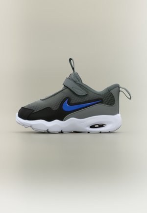 Šedo-čierna teniska Nike s modrým logom Swoosh, bielou podrážkou, suchým zipsom a pútkami na jazyku a päte, zobrazená z bočného pohľadu.