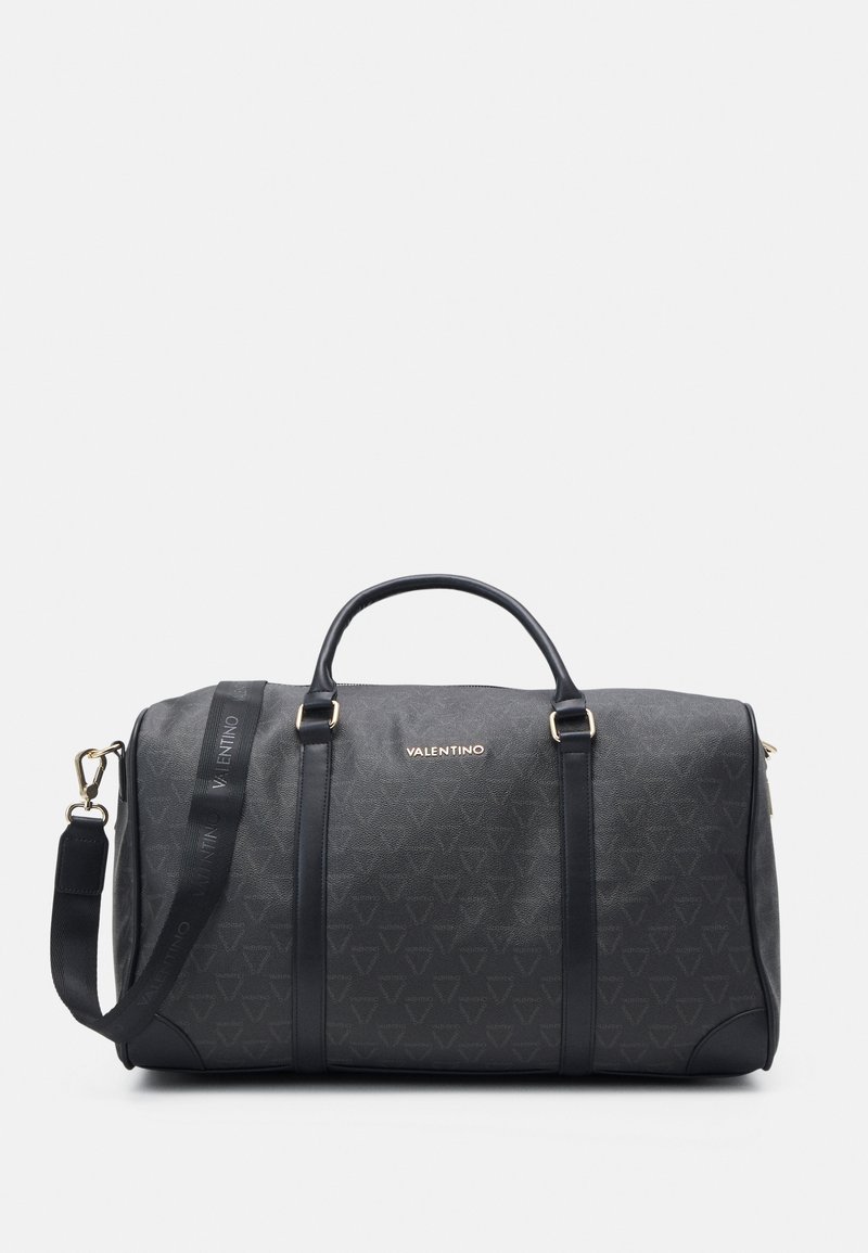 Saco duffel preto com acabamento texturizado, apresentando acabamentos em dourado, duas alças e uma alça ajustável. Logotipo em relevo na lateral.