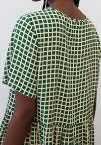 Vestido a cuadros verdes con un corte holgado, escote redondo y mangas cortas, hecho de tela ligera con un dobladillo en capas.