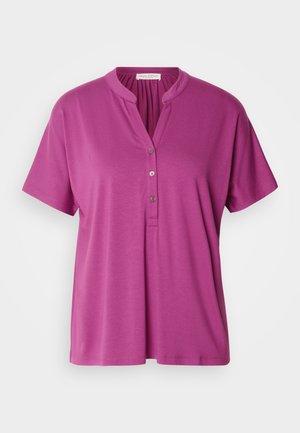 Blouse violette à manches courtes avec col mandarin et patte de boutonnage à trois boutons. Fabriquée dans un tissu lisse et léger. Design simple.