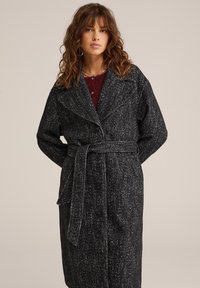 Črno-bele plašč z vzorcem ribje kosti, z pasom, velikim ovratnikom in gumbom za zapiranje. Teksturojeno volneno blago. Dolgi rokavi.