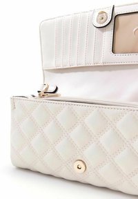 Sac à main blanc matelassé avec une texture lisse, de forme rectangulaire, accents en métal doré et une poche zippée avec un emplacement transparent pour une carte d'identité.