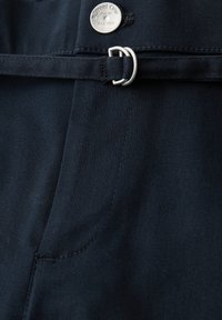 Pantalon en tissu bleu marine foncé avec une ceinture assortie passée à travers une boucle à double anneau en D argentée et un bouton métallique estampillé "Street One".