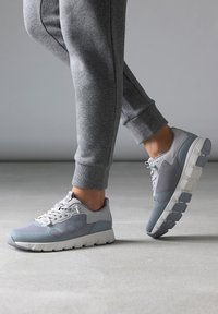 Chaussures de sport légères en gris et blanc, présentant une tige en maille, une semelle rembourrée et des accents texturés pour une traction et un soutien.
