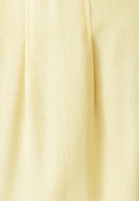 Mīksts dzeltenas krāsas audums ar smalku austu faktūru un vieglām vertikālām krokām.