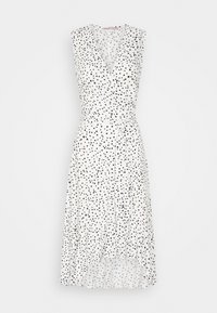 Robe sans manches blanche avec un design croisé, ornée de pois noirs sur toute sa surface et d'une ceinture nouée à la taille. Jupe évasée avec un ourlet volanté.