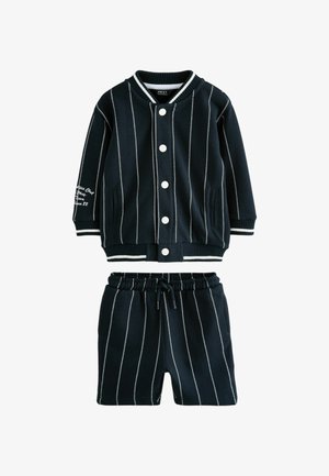 Conjunto din două piese cu dungi alb-negru, format dintr-o jachetă cu nasturi și guler ribat, și pantaloni scurți cu talie elastică și buzunare.