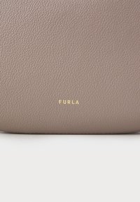 Borsa in pelle marrone dalla texture ruvida con finitura liscia, caratterizzata da un logo "FURLA" in rilievo dorato al centro in basso.