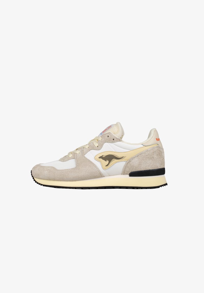Sneaker beige e bianco realizzato in materiali scamosciati e mesh, con un logo giallo a contrasto e una suola in gomma nera.