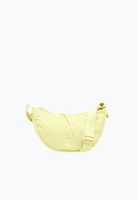 Borsa a tracolla giallo pallido a forma di mezzaluna con tracolla regolabile e chiusura con cerniera superiore su sfondo bianco.