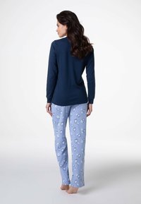 Maglietta a maniche lunghe blu navy abbinata a pantaloni del pigiama azzurri chiari con motivo a nuvole, entrambi realizzati in tessuto morbido e confortevole.