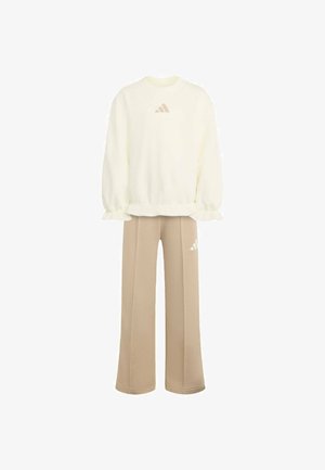 Crèmekleurige trui met lange mouwen en gerimpelde boorden, gecombineerd met beige wijde broek, beide met een klein Adidas-logo.