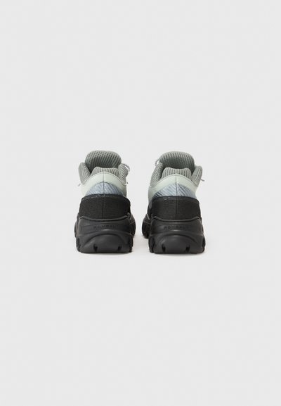 Graue und schwarze Turnschuhe mit einem strukturierten Mesh-Obermaterial und Gummisohle; verfügen über einen gepolsterten Schaft und reflektierende Akzente.