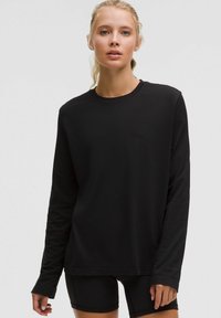 Schwarzes Langarmshirt aus weichem Material, mit Rundhalsausschnitt und lockerer Passform. Glatte Textur, schlichtes Design, keine sichtbaren Muster.