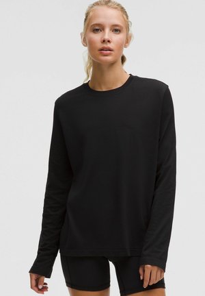 Zwarte lange mouwen shirt, gemaakt van zachte stof, heeft een ronde halslijn en een relaxte pasvorm. Soepele textuur, eenvoudig ontwerp, geen zichtbare patronen.