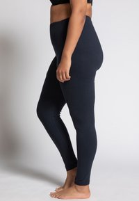 Námornícke modré legíny vyrobené z elastického materiálu, so širokým pásom a hladkým, priliehavým strihom cez nohy.