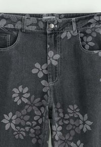 Jean en denim gris avec un motif floral dans une teinte légèrement plus claire. Comprend une fermeture à bouton à l'avant et un design de poches standard.