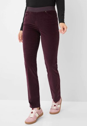 Bordeaux corduroy broek met een rekbare tailleband, voorzien van twee voorzakken en een strakke, rechte pasvorm. Gepaard met lichtroze sneakers.