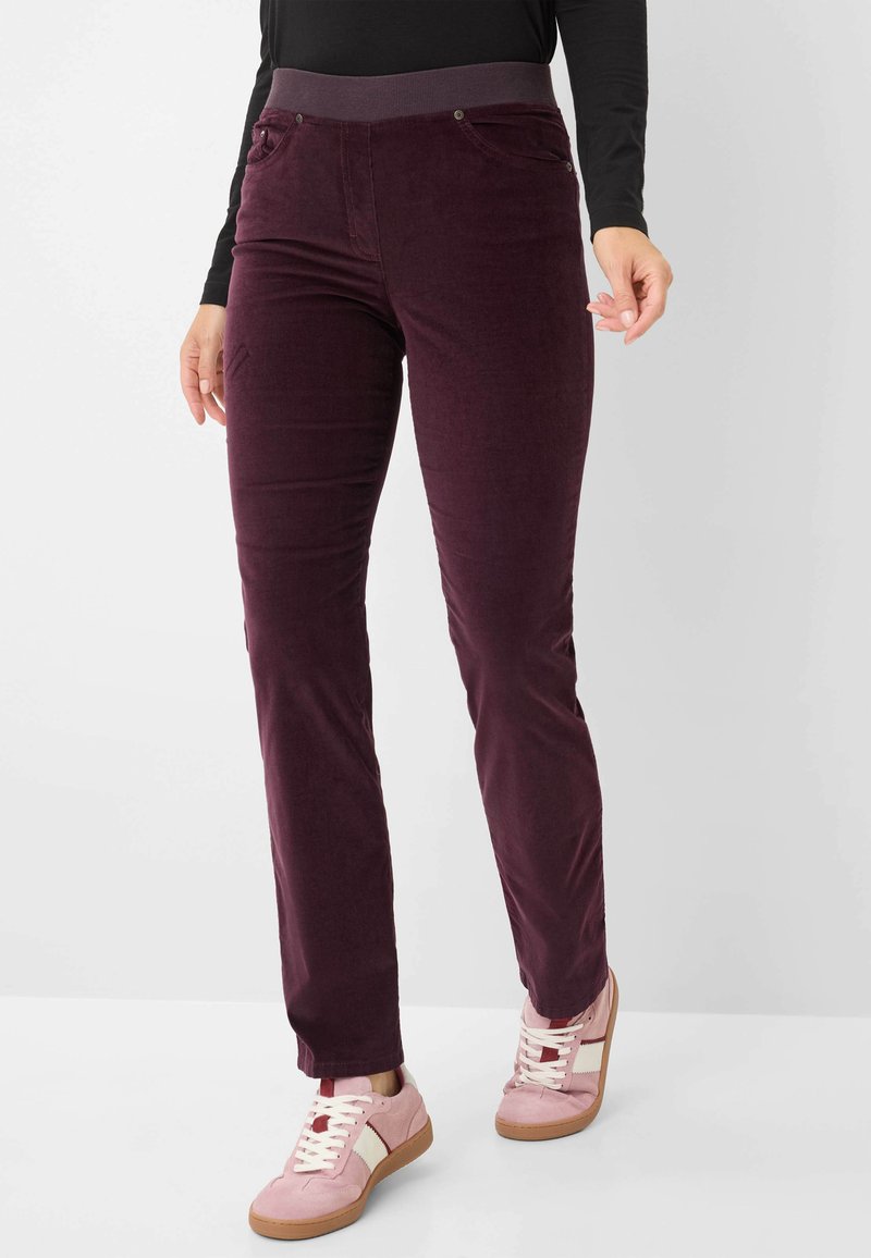 Burgunderfarbene Cordhose mit dehnbarem Bund, ausgestattet mit zwei Vorderreißverschlusstaschen und einem eleganten, geraden Bein. Kombiniert mit hellrosa Sneakers.