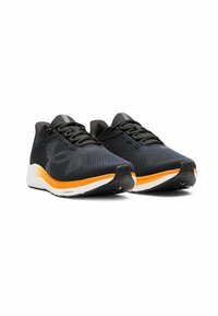 Baskets noires de sport avec tige en maille, finition texturée, bandes d'accent orange sur la semelle blanche, et semelle extérieure en caoutchouc noir pour une meilleure traction.