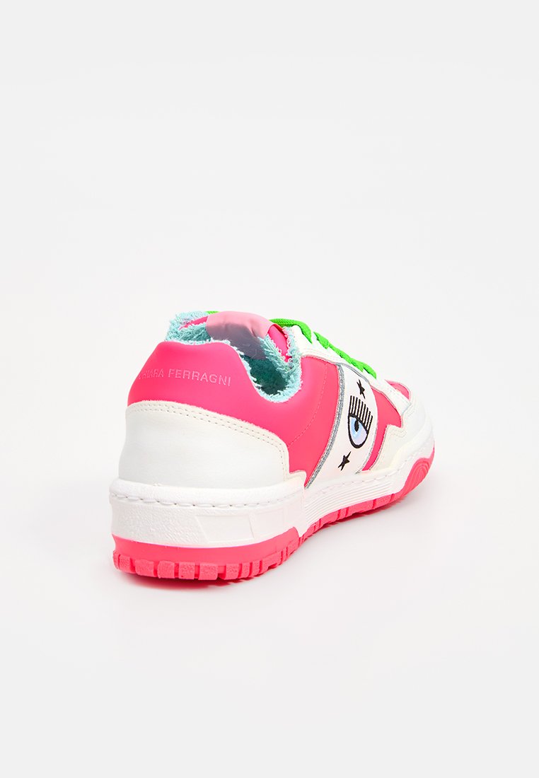 Różowe i białe sneakersy o masywnej konstrukcji, z zielonymi sznurówkami, teksturowanym wewnętrznym wykończeniem oraz dekoracyjnymi akcentami w postaci oka i gwiazd.