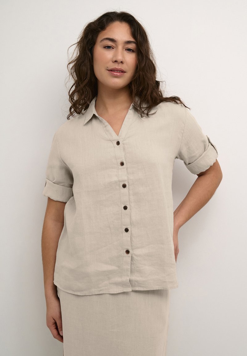 Beige linnen button-up overhemd met korte opgerolde mouwen, een kraag en houten knopen aan de voorkant. Relaxte pasvorm met een licht gebogen zoom.