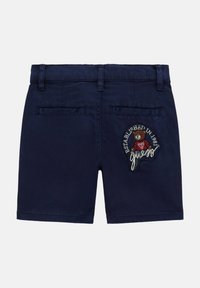 Navyblaue Shorts aus einem Stoff mit glatter Textur; mit aufgesticktem Bärenlogo und dem Text "Established in 1981" auf der Rückseite.