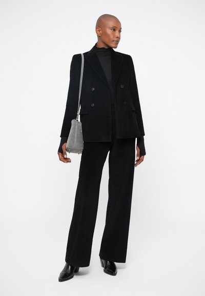 Black corduroy double-breasted blazer paired with matching wide-leg trousers. Accessories include a small gray suede bag and black heeled shoes.